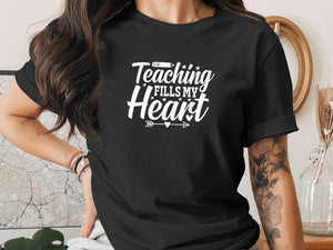 Black t-shirt with white text "Teaching fills my heart" and arrow graphic.