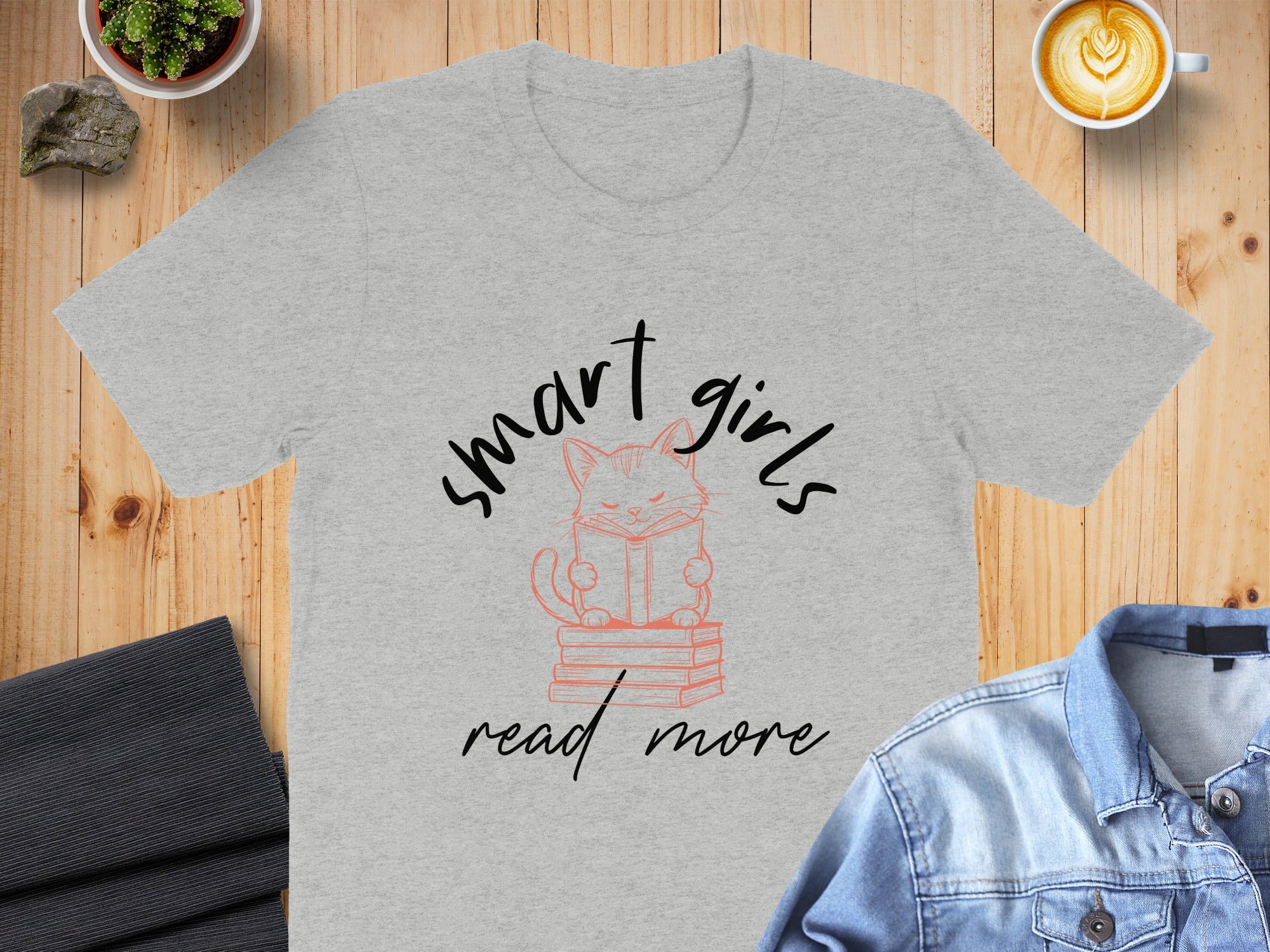 Grey T-shirt with illustration of cat reading on books, text "smart girls read more".