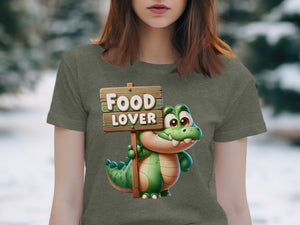 Cartoon alligator holding a "FOOD LOVER" sign on a green t-shirt.