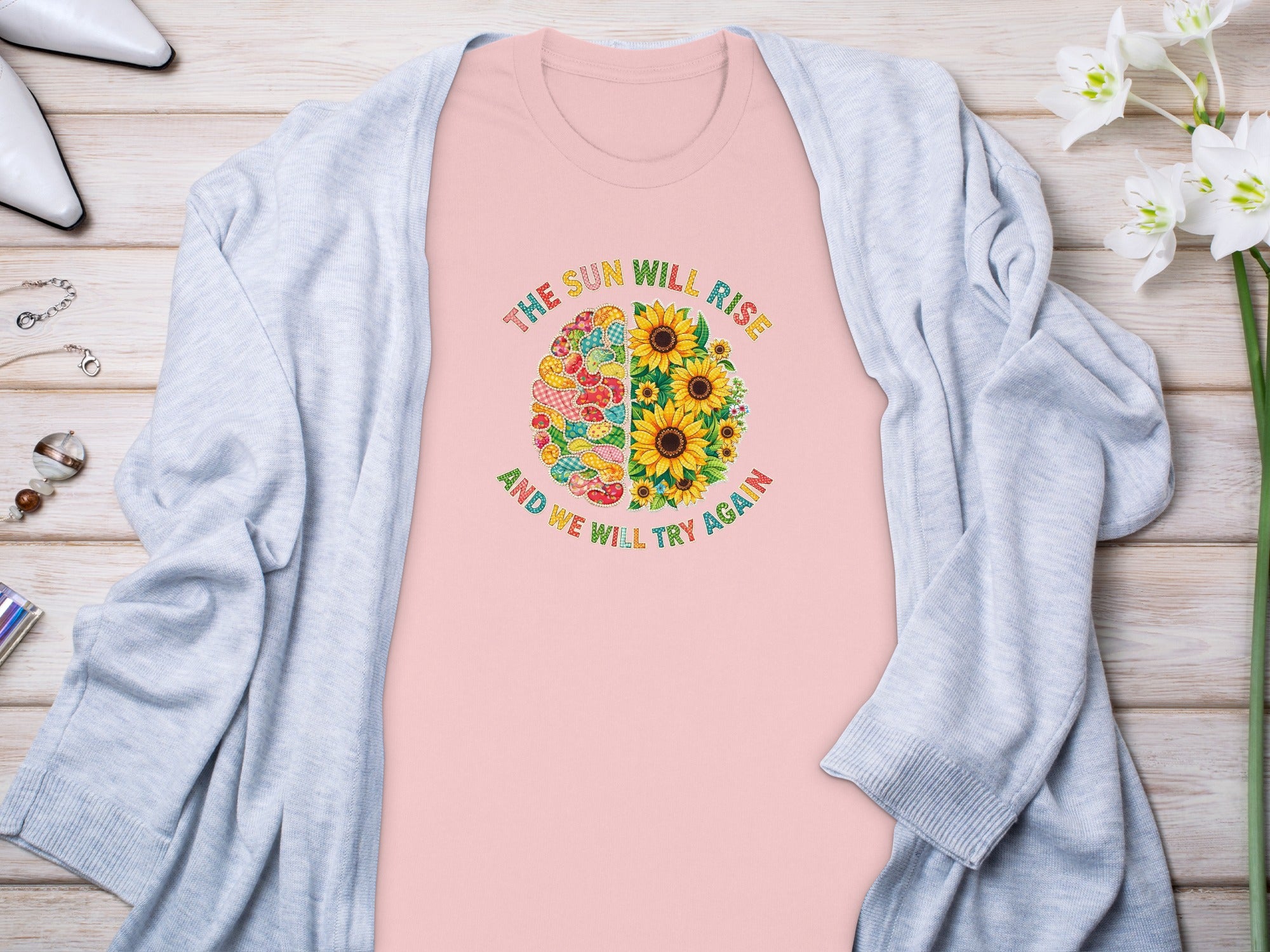 Pink t-shirt with "The sun will rise and we will try again" graphic on a brain design.