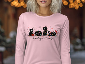 A person wearing a light pink long-sleeve shirt with an illustration of four black cats and the text "merry catmas."