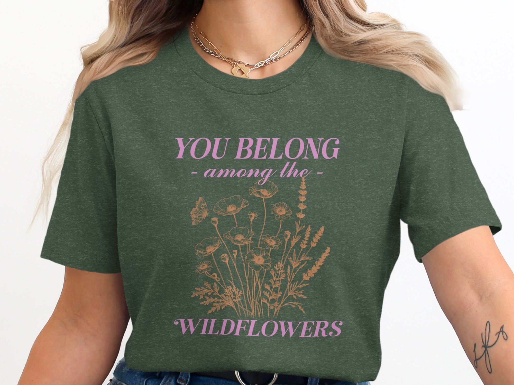 Dark green t-shirt with pink text "YOU BELONG - among the - WILDFLOWERS" and floral design.