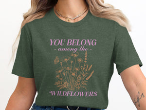 Dark green t-shirt with pink text "YOU BELONG - among the - WILDFLOWERS" and floral design.