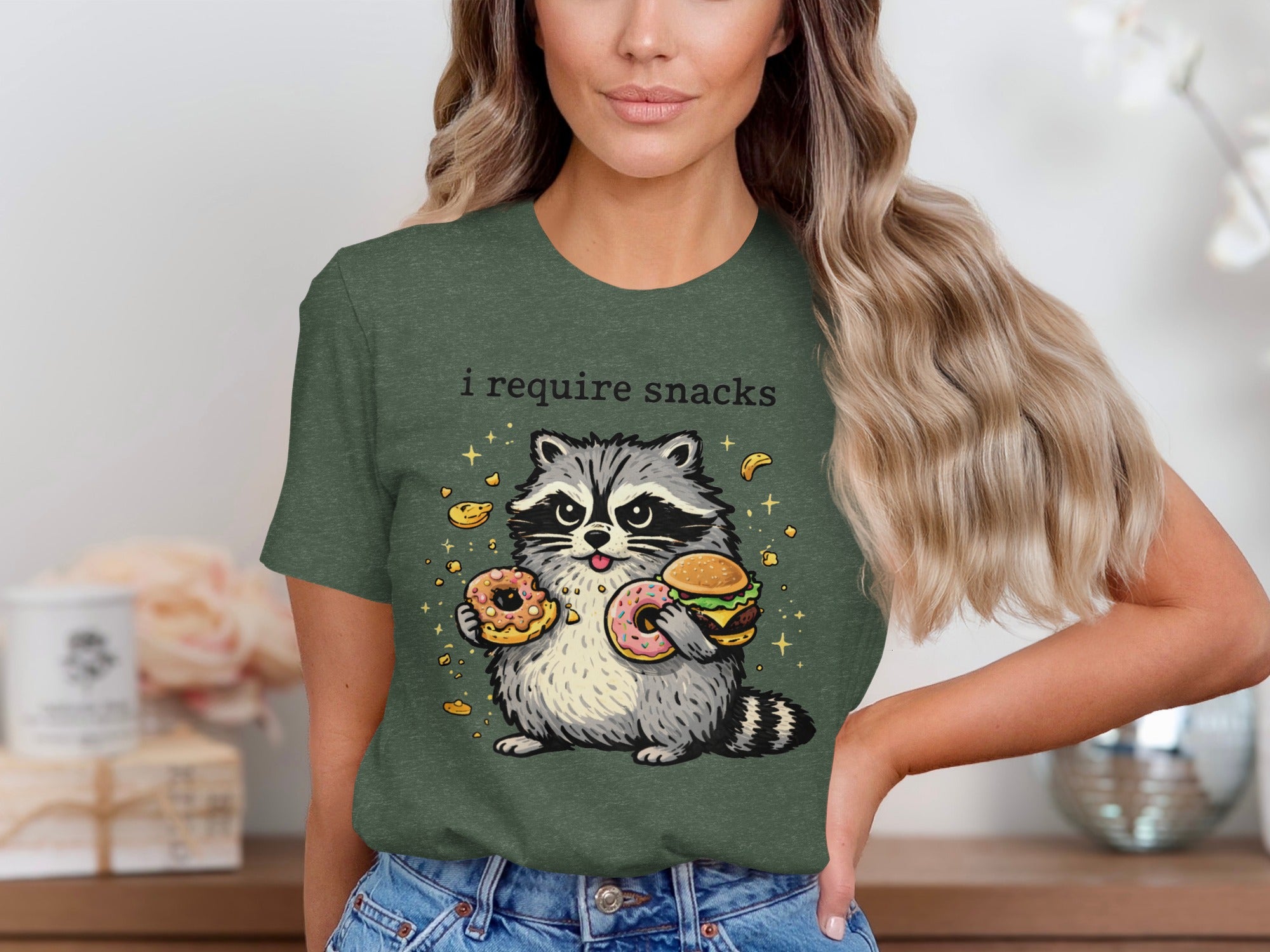 T-shirt graphic of a raccoon holding donuts and a burger, with "i require snacks" text above.