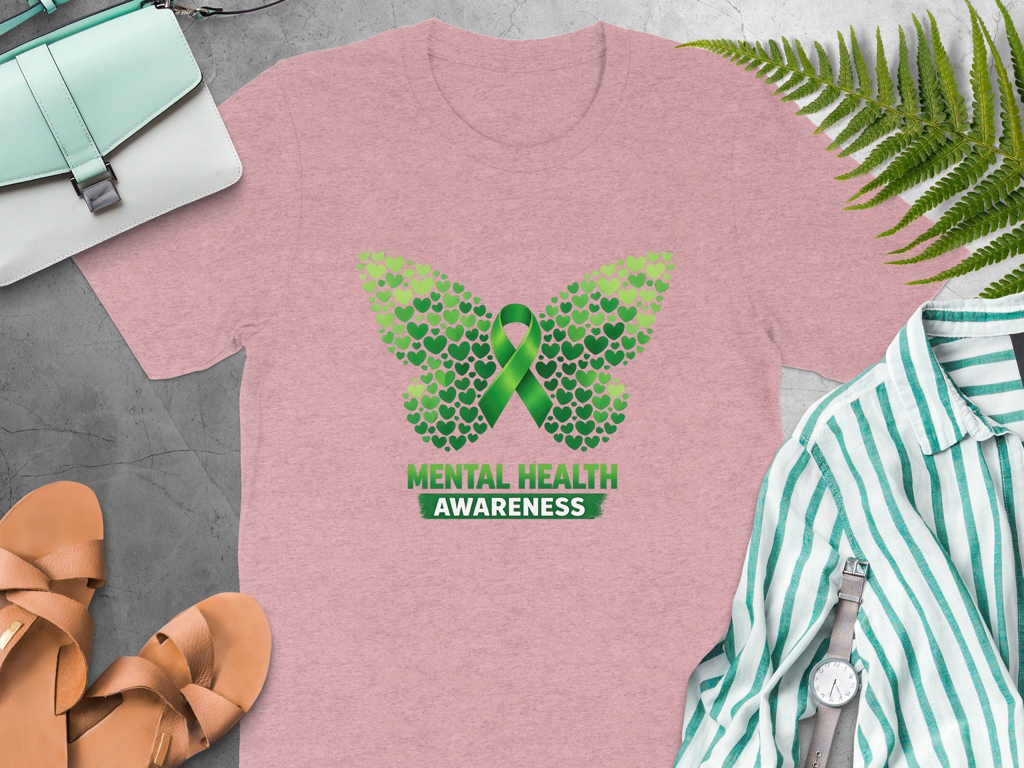 Pink t-shirt with butterfly made of green hearts and "Mental Health Awareness" text.