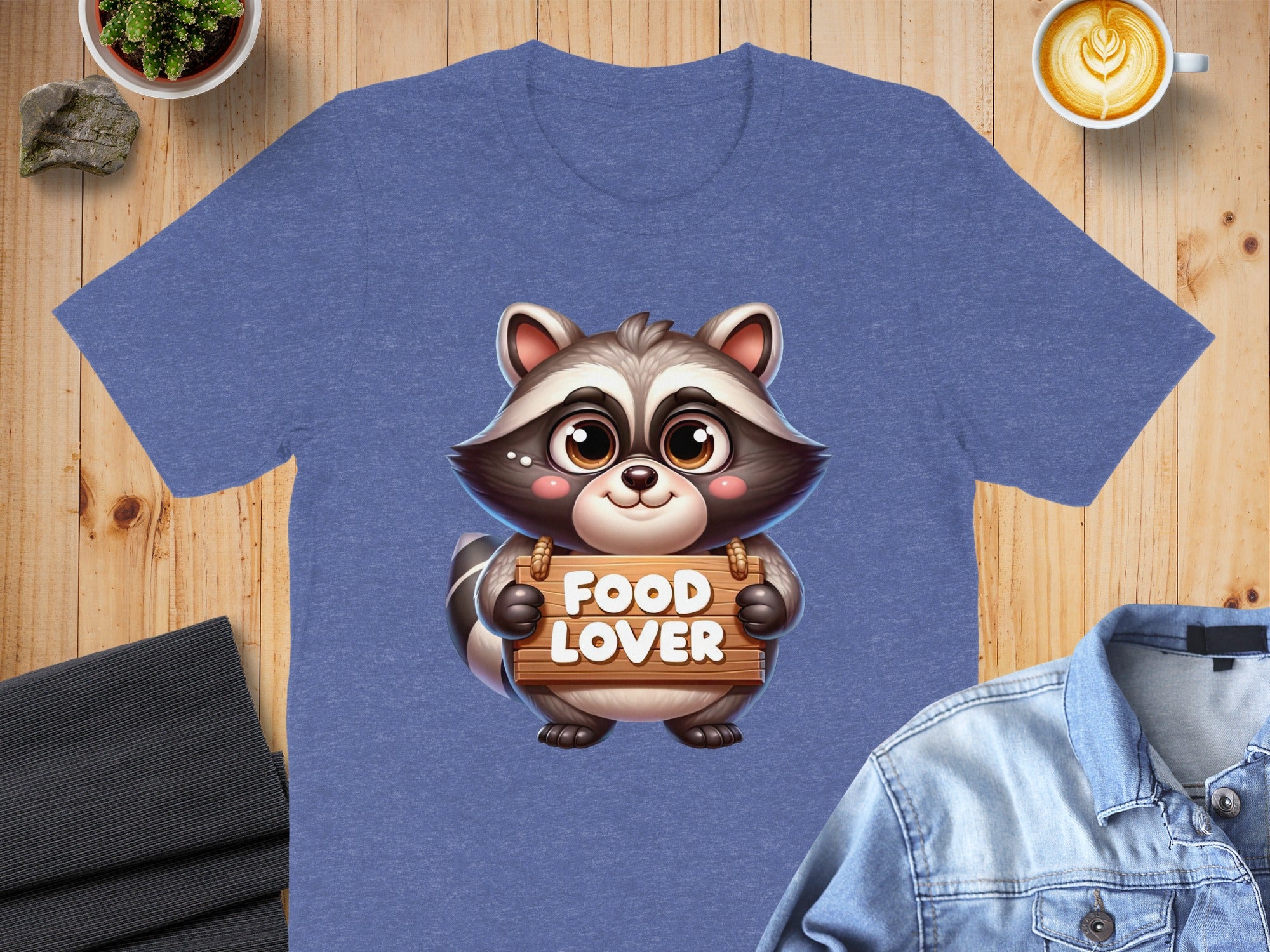 Cartoon raccoon holding a "FOOD LOVER" wooden sign on a t-shirt.