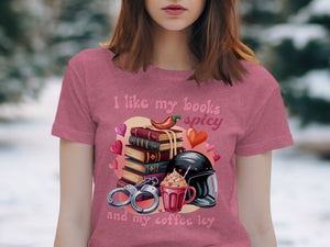 "I like my books spicy and my coffee icy" text on a pink shirt with books, chili, coffee, and handcuffs.