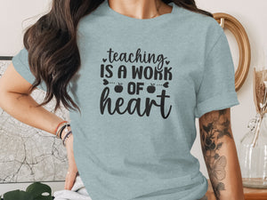 Light blue t-shirt with black text: "teaching IS A WORK OF heart"