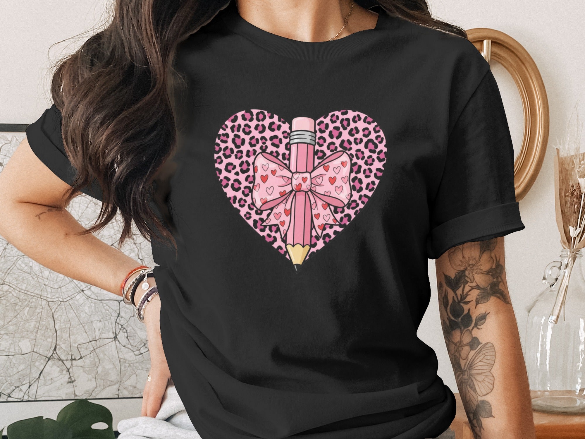 Black t-shirt with pink leopard heart, pencil, and bow graphic.