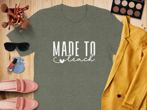Green t-shirt with white text "MADE TO teach" and a heart.