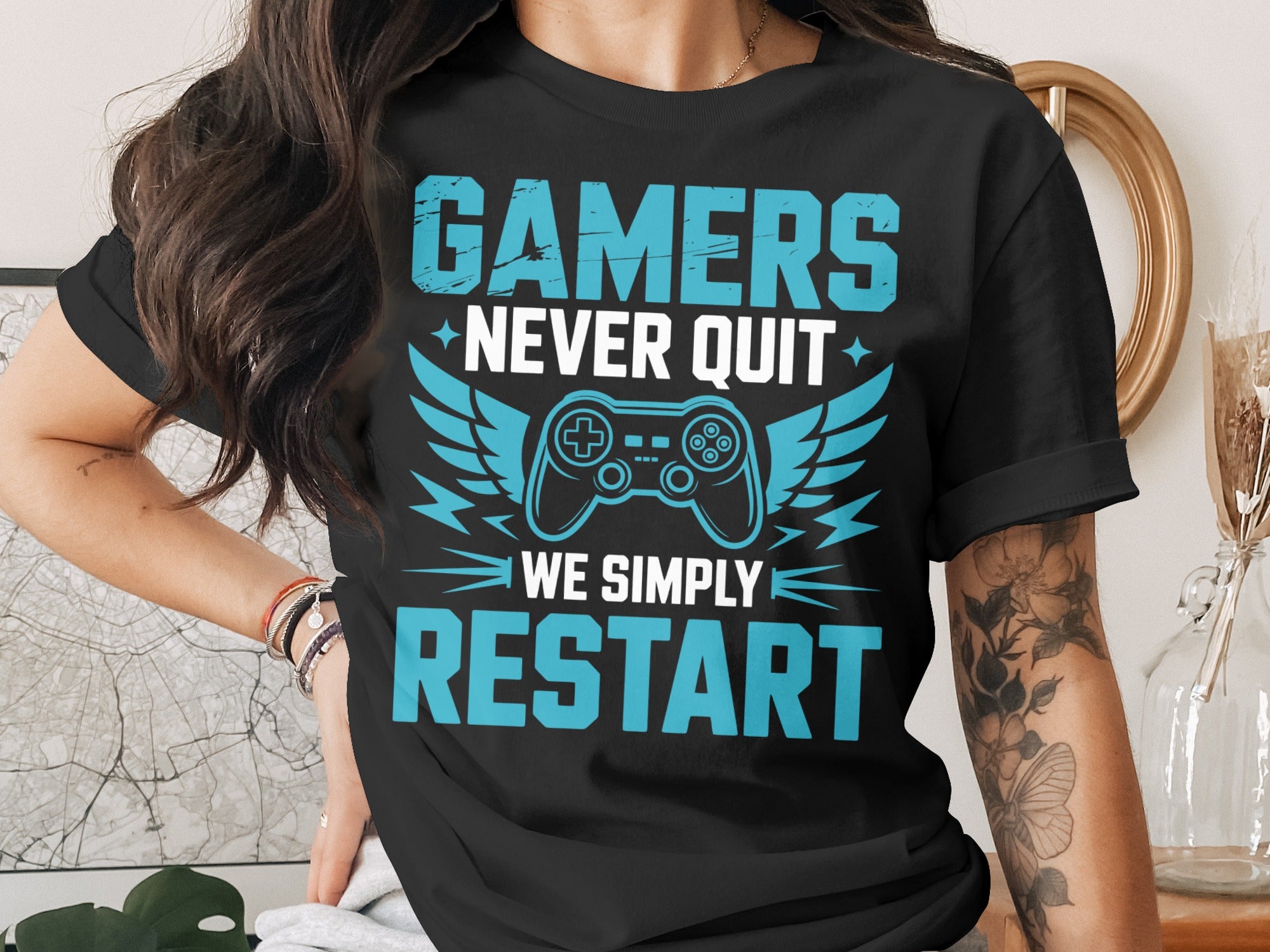 Black t-shirt with blue text: "GAMERS NEVER QUIT WE SIMPLY RESTART"