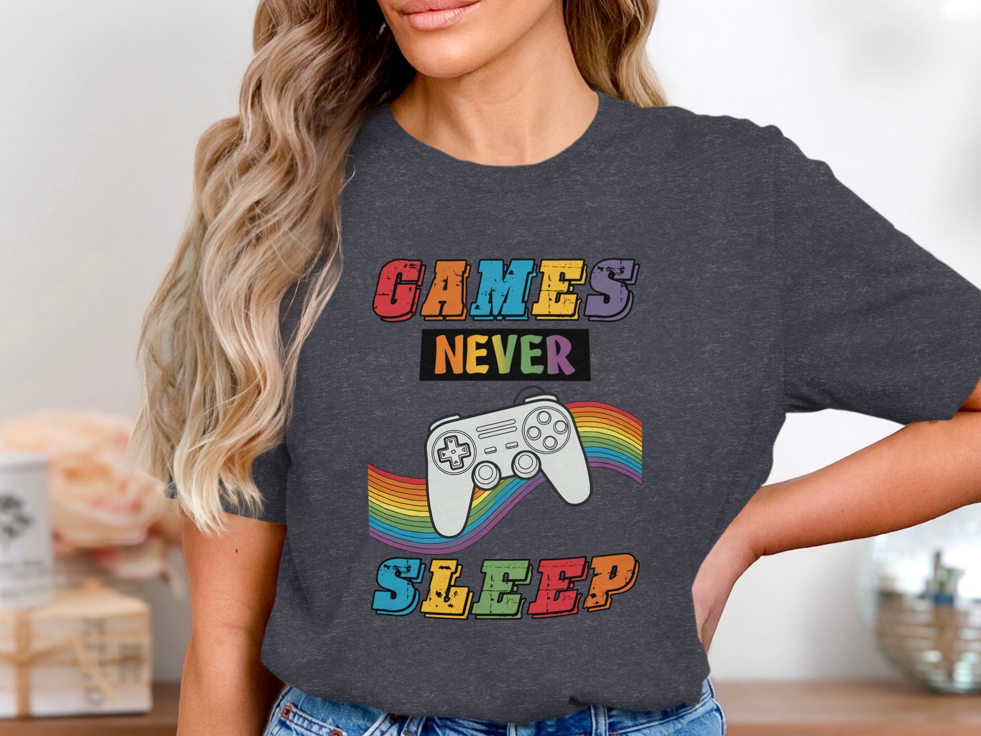 T-shirt design with text "GAMES NEVER SLEEP" and a rainbow-striped video game controller.