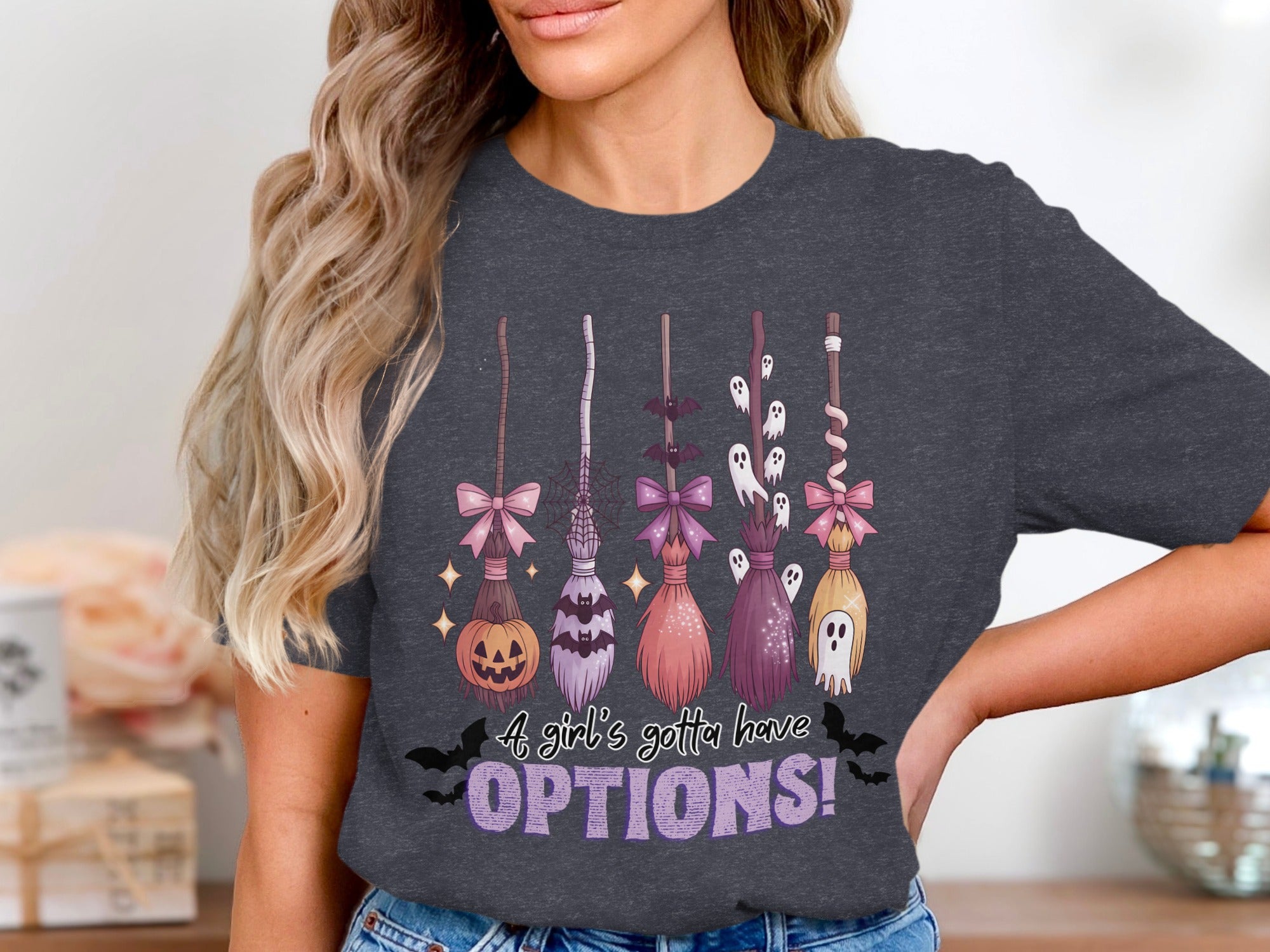 Halloween graphic tee with brooms, pumpkin, bats, ghosts, and text.