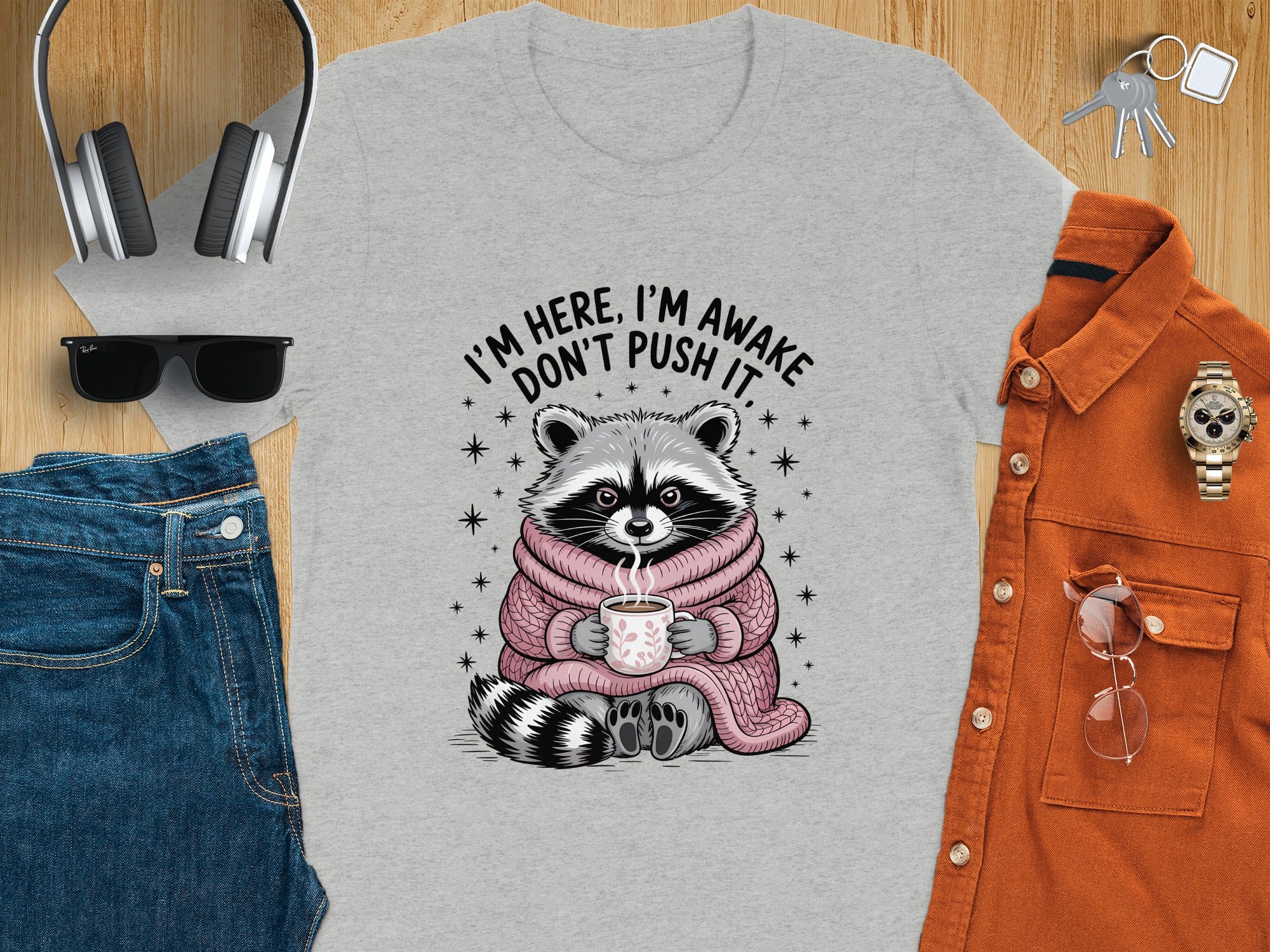 T-shirt with a raccoon holding a coffee cup, text says "I'M HERE, I'M AWAKE DON'T PUSH IT."