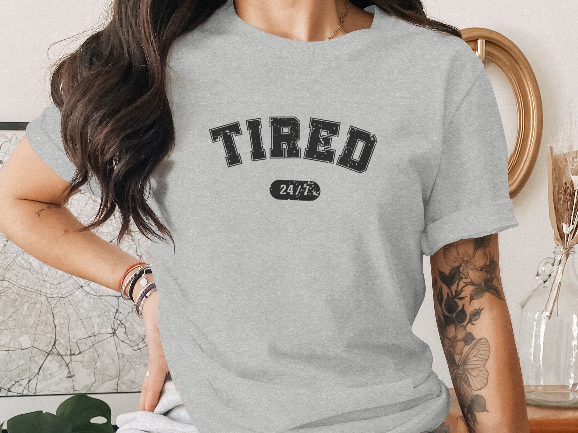Grey t-shirt with black text "TIRED 24/7" and a butterfly tattoo.