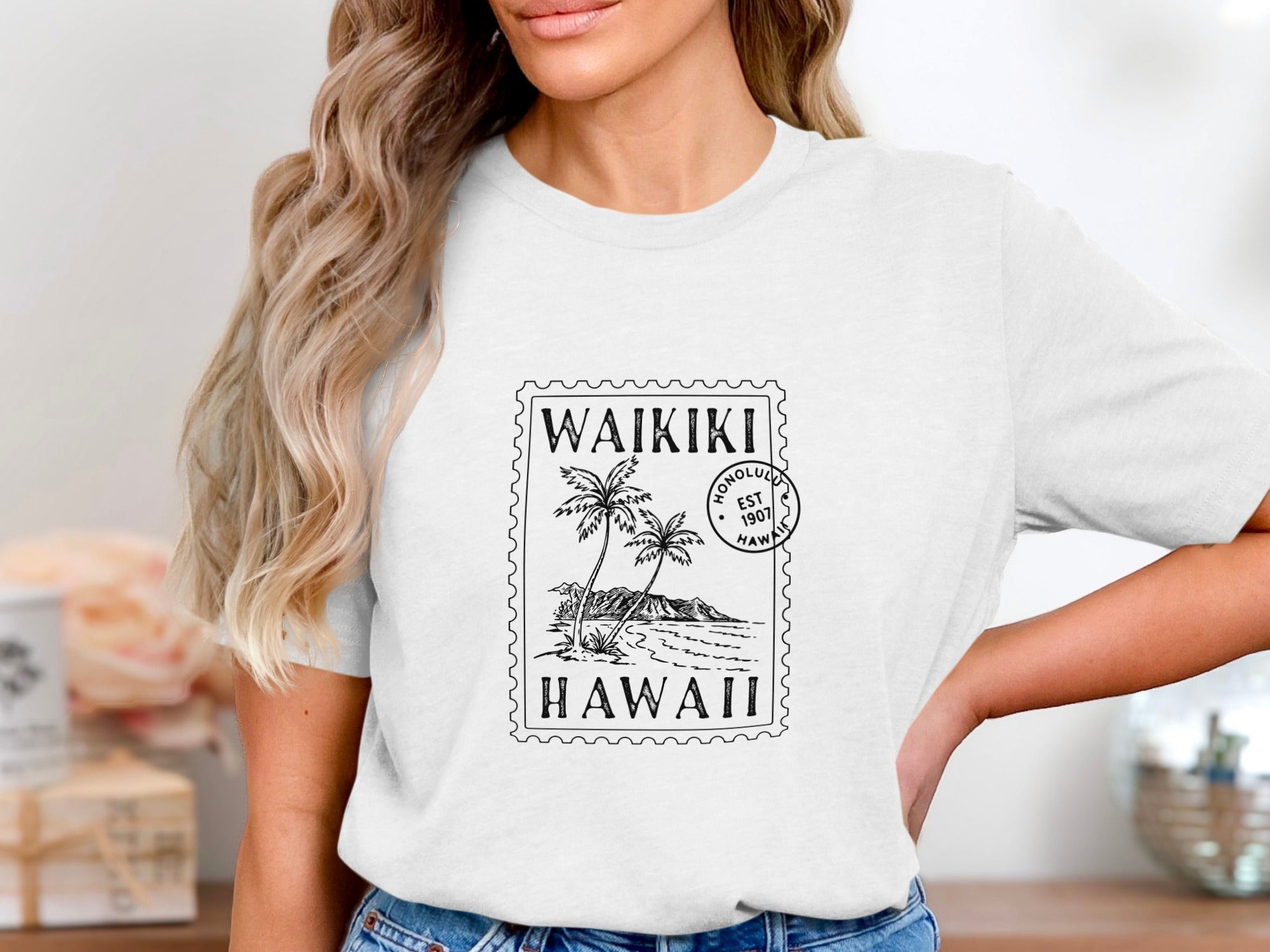 White t-shirt with "Waikiki Hawaii" stamp design featuring palm trees and mountains.