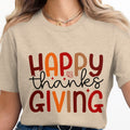 Light brown t-shirt with "Happy Thanksgiving" text and autumn leaf graphic.