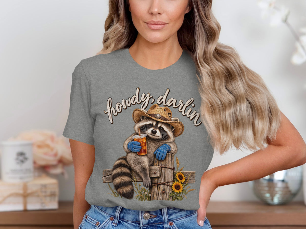 Raccoon in cowboy hat and gloves holds drink with "howdy, darlin" text.