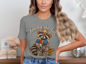 Raccoon in cowboy hat and gloves holds drink with "howdy, darlin" text.