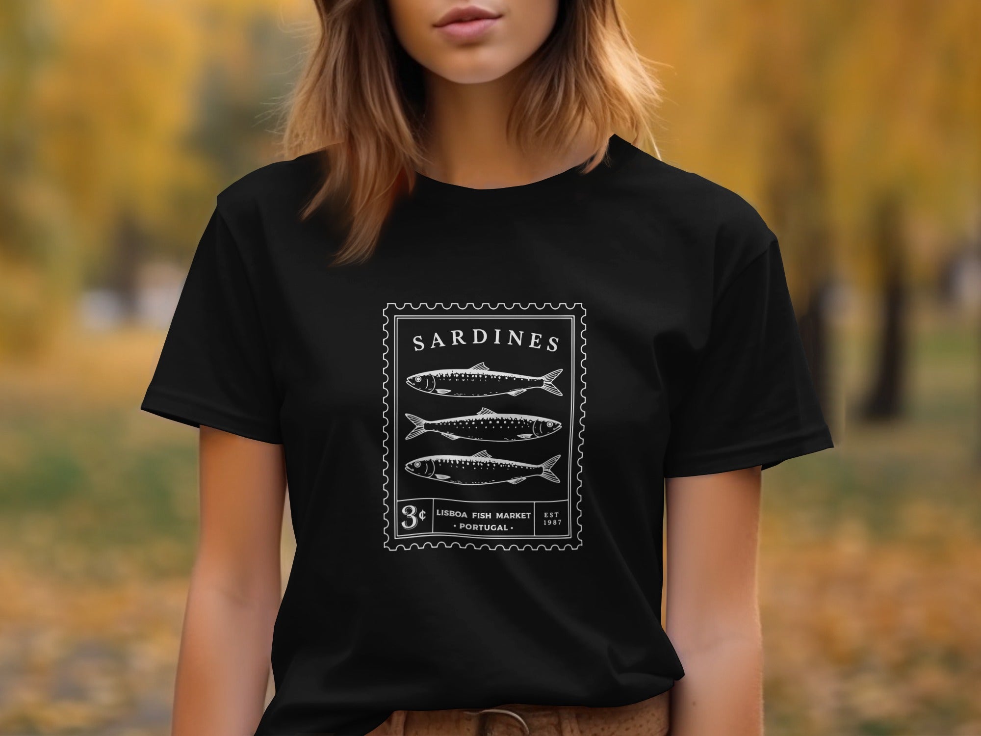 Black t-shirt with a stamp graphic featuring three sardines and "Sardines Lisbon Fish Market Portugal" text.