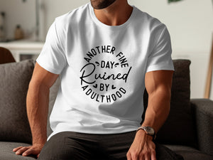 White t-shirt with black text that reads "Another fine day ruined by adulthood."
