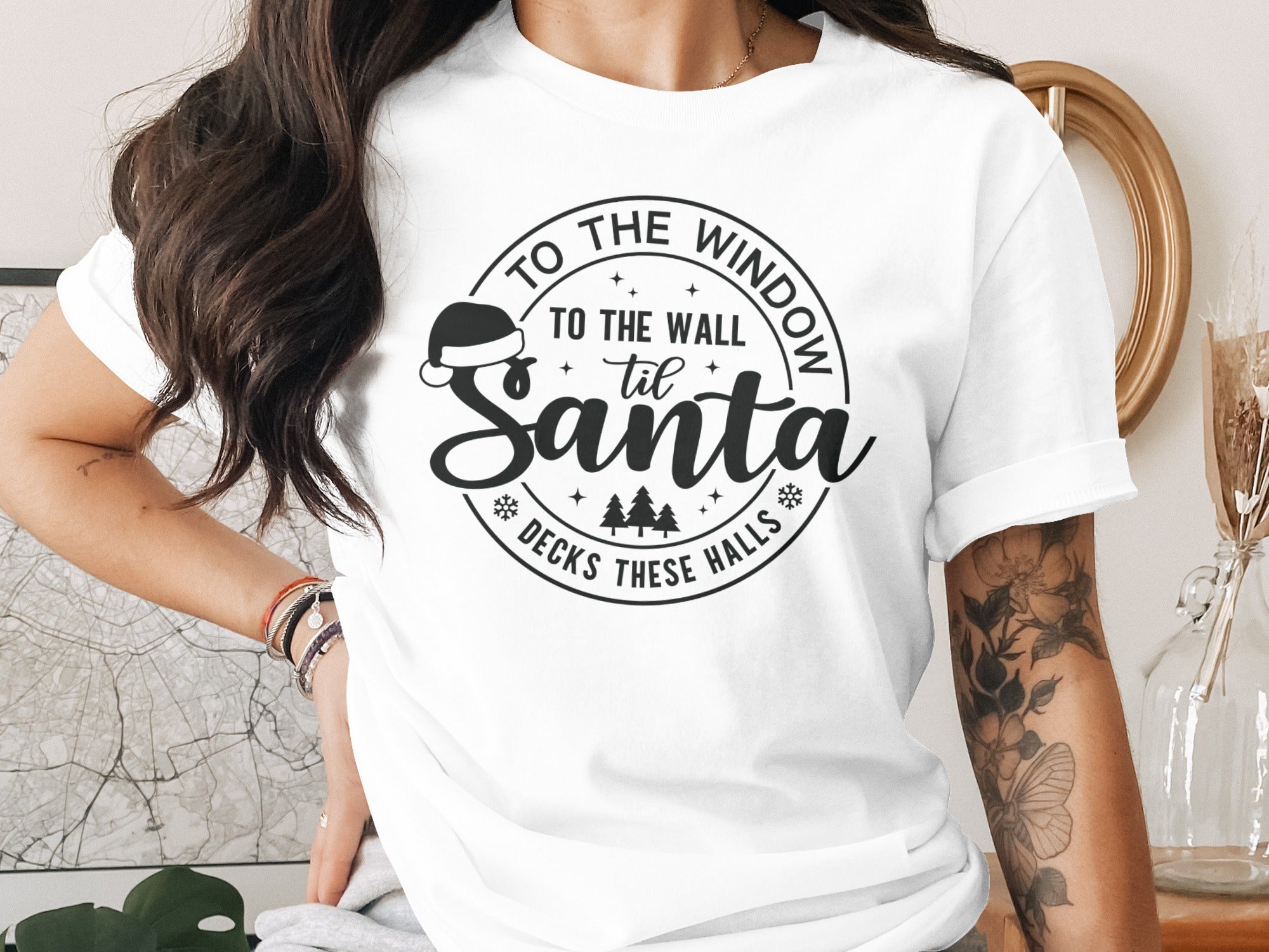 White t-shirt with black text: "To the window to the wall 'til Santa decks these halls"