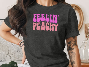 Dark grey t-shirt with pink and purple "Feelin' Peachy" text and stars design.