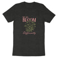 Dark grey t-shirt with "WE ALL BLOOM Differently" text and floral design.