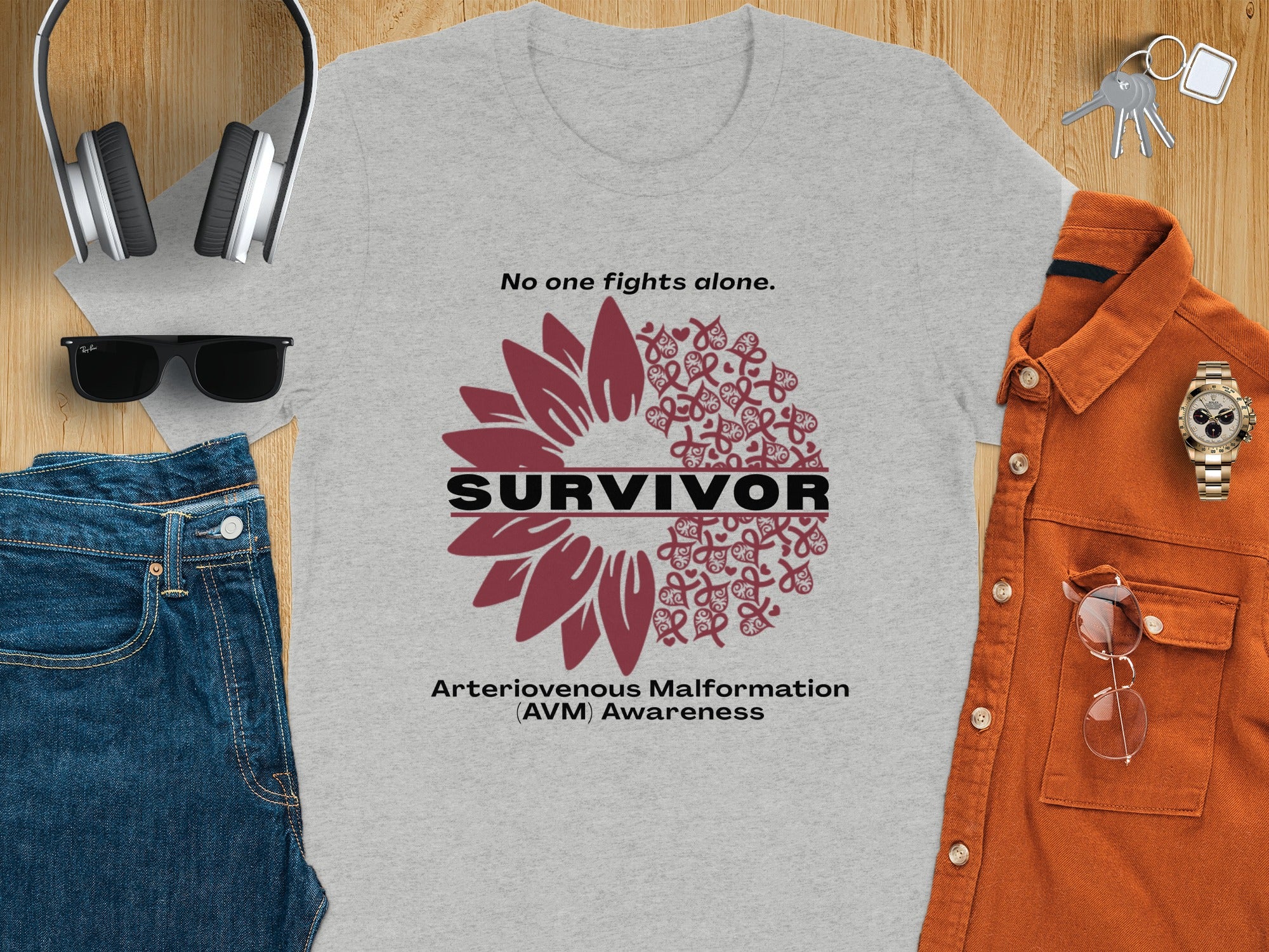 Gray t-shirt with "No one fights alone. SURVIVOR. Arteriovenous Malformation (AVM) Awareness" text and sunflower graphic.