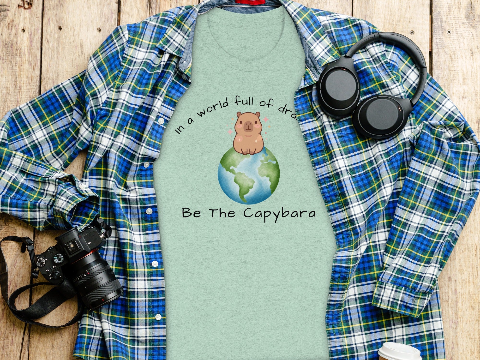 Light green t-shirt with capybara on a globe graphic and text "Be The Capybara".