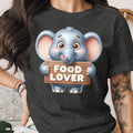 Cute cartoon elephant holding a "FOOD LOVER" sign on a dark t-shirt.