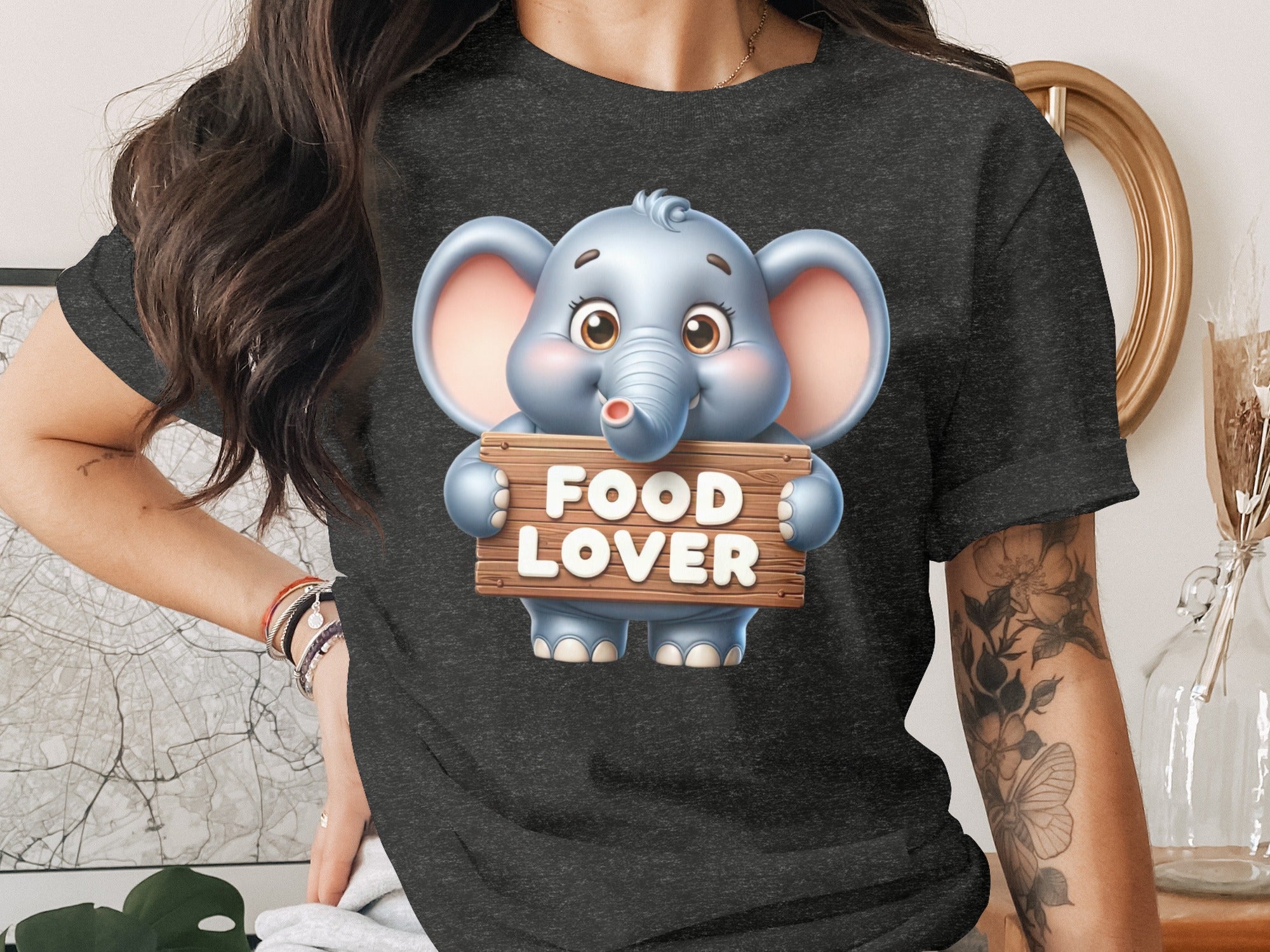 Cute cartoon elephant holding a "FOOD LOVER" sign on a dark t-shirt.