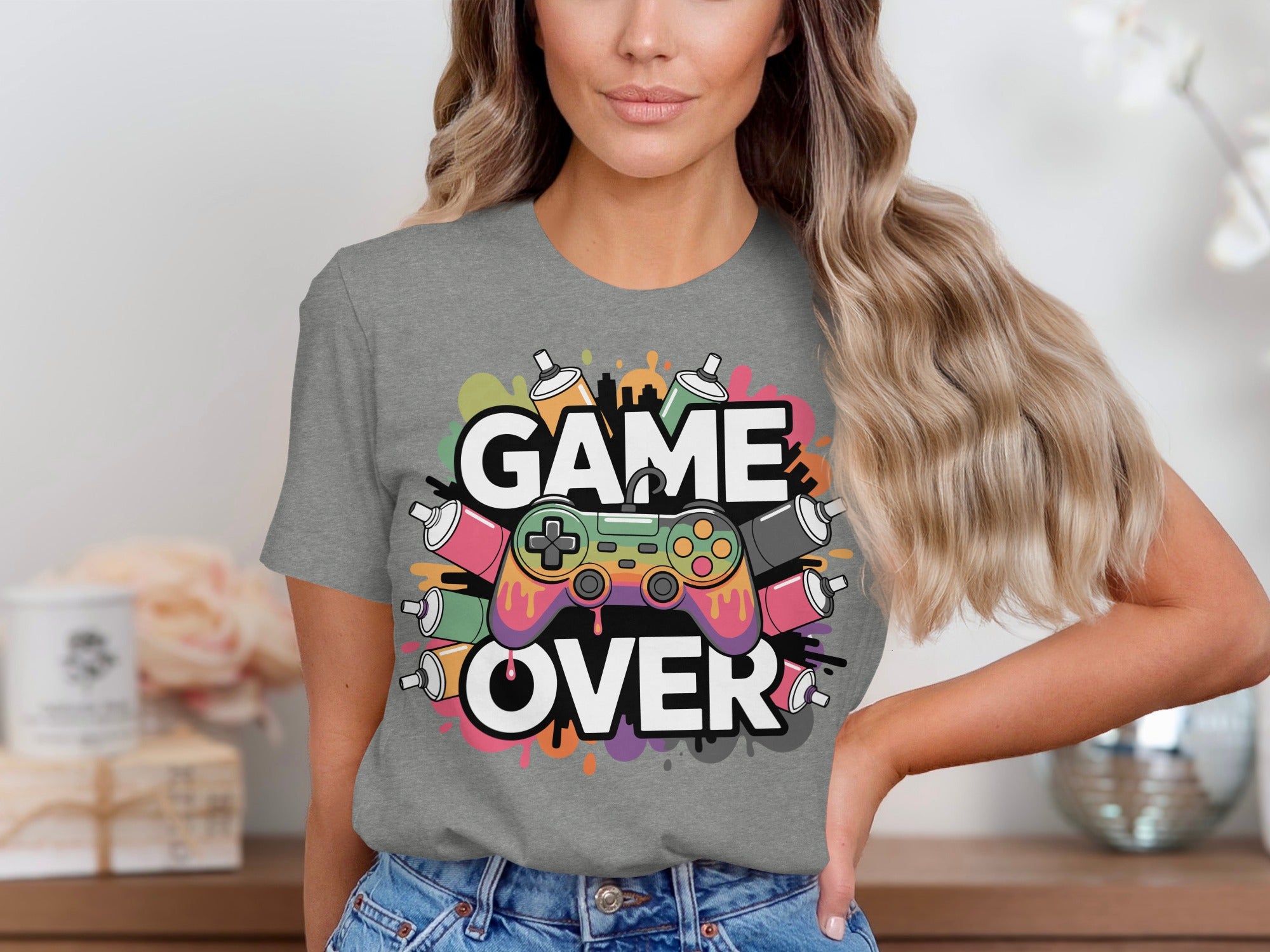 Grey t-shirt with "GAME OVER" text and a colorful gaming controller surrounded by spray paint cans.