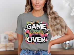 Grey t-shirt with "GAME OVER" text and a colorful gaming controller surrounded by spray paint cans.