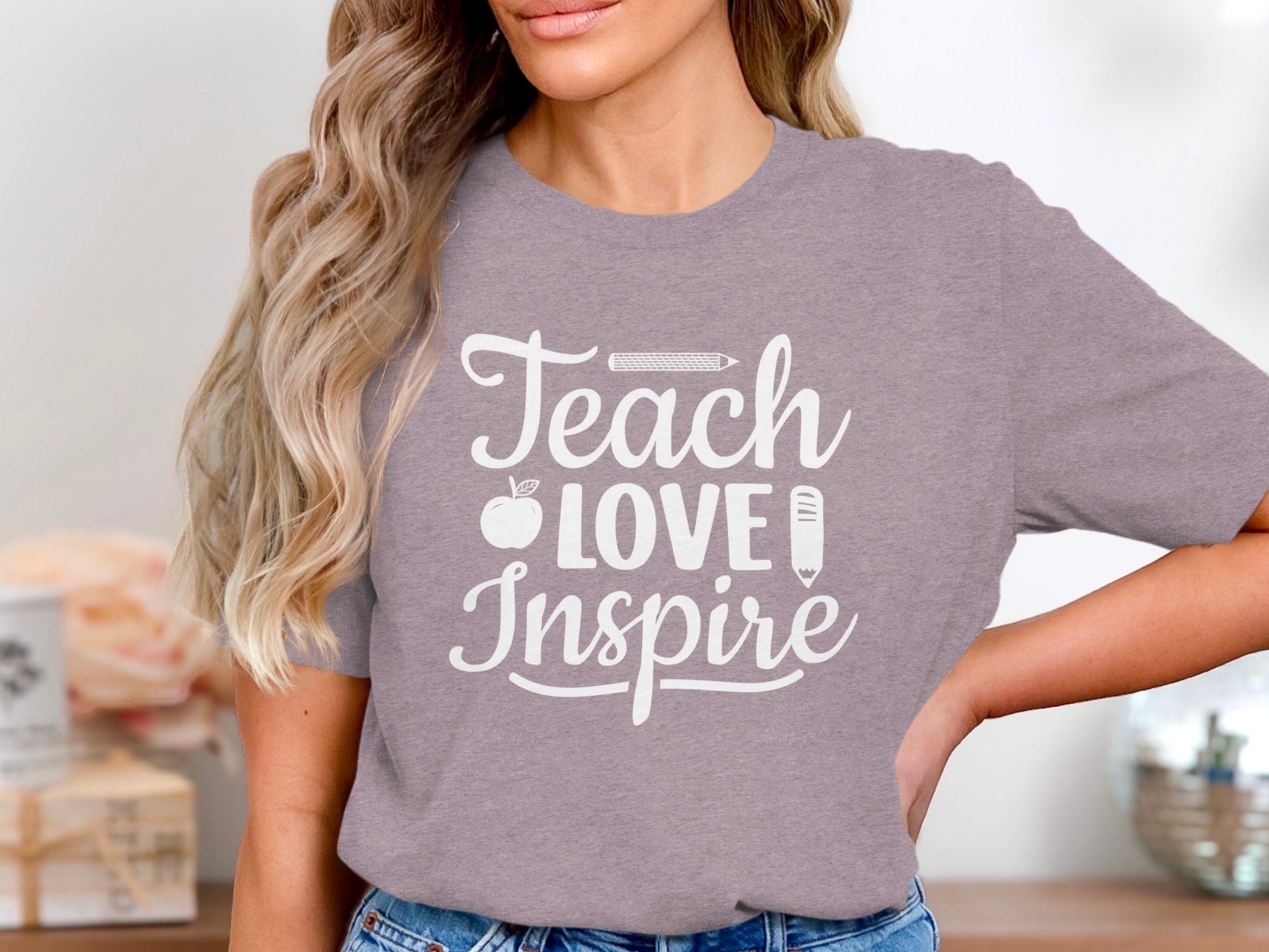 Woman wears lilac t-shirt with white text "Teach Love Inspire" and icons.