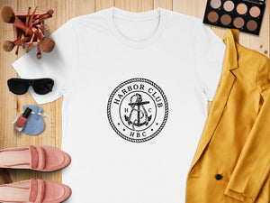 White t-shirt with "Harbor Club HBC" anchor logo, gold blazer, pink loafers, sunglasses, and makeup.