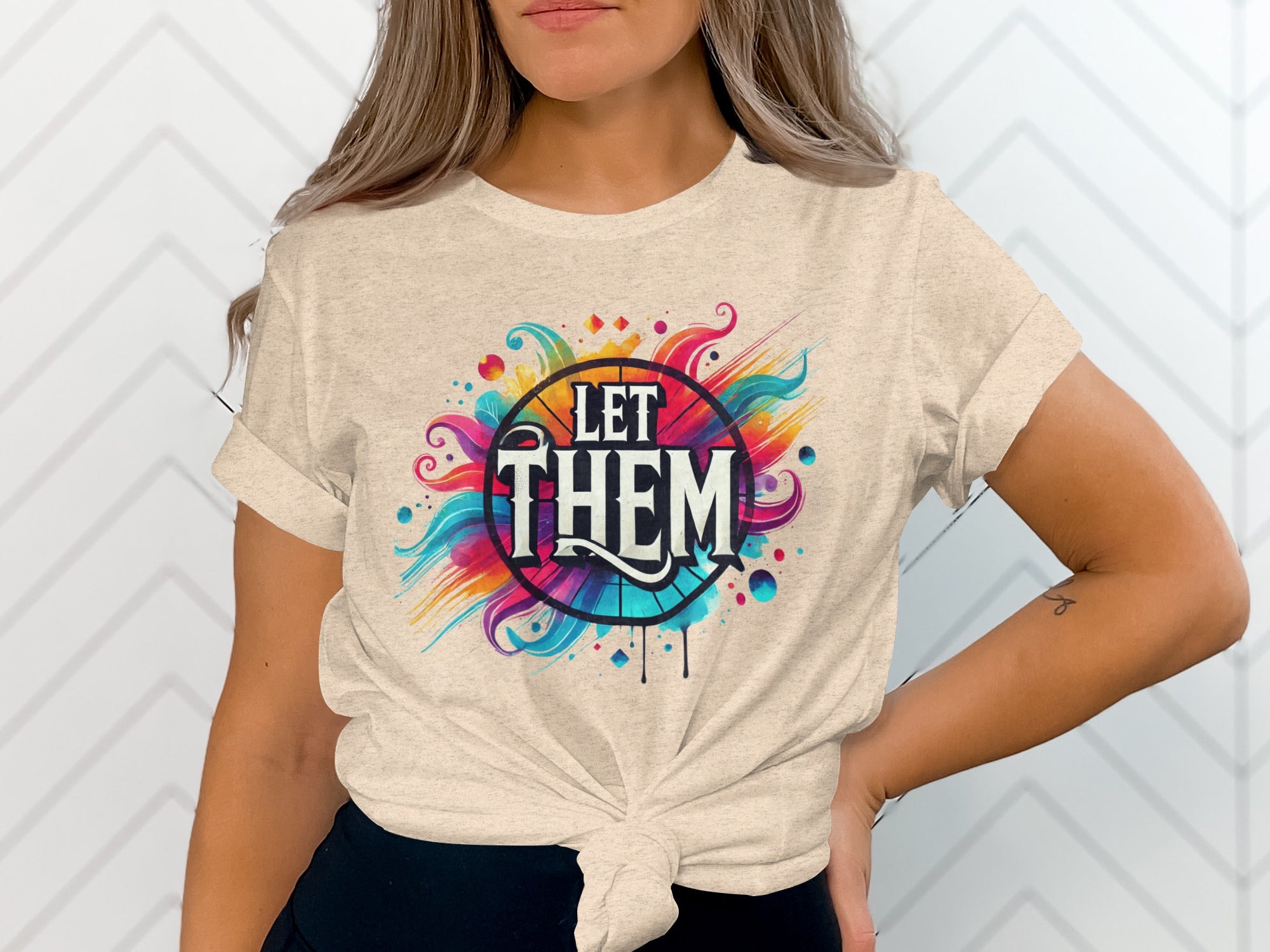 Light-colored t-shirt with colorful "LET THEM" text and abstract design.