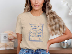 Beige t-shirt with blue stamp graphic of sardines, "Sardines", "Lisbon Fish Market", and "Portugal".