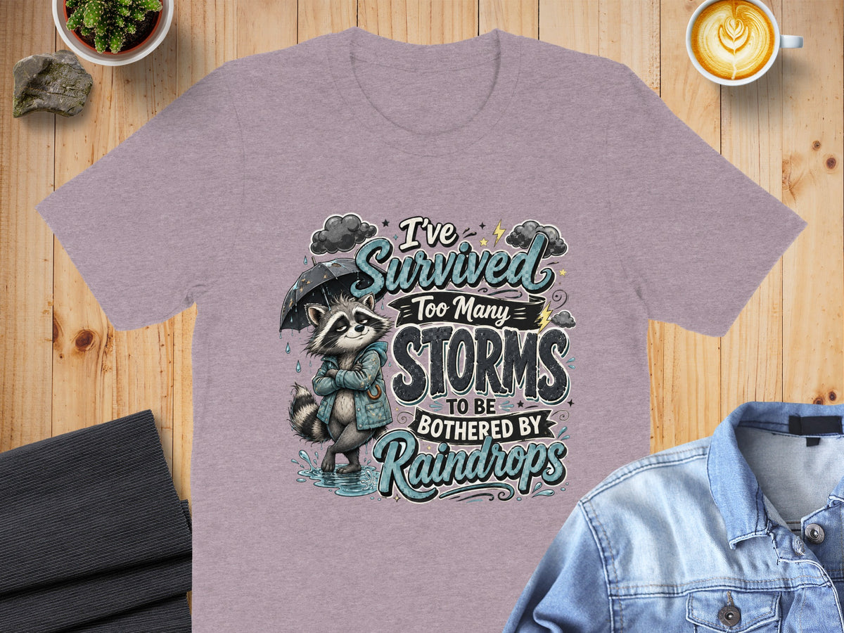 T-shirt with raccoon graphic and text: I've survived too many storms to be bothered by raindrops.