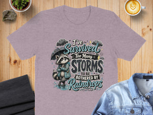 T-shirt with raccoon graphic and text: I've survived too many storms to be bothered by raindrops.