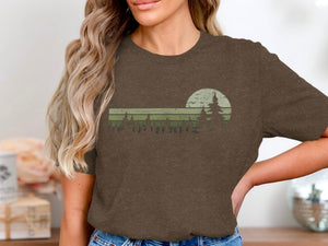 Brown t-shirt with a retro sunset and pine trees graphic design.