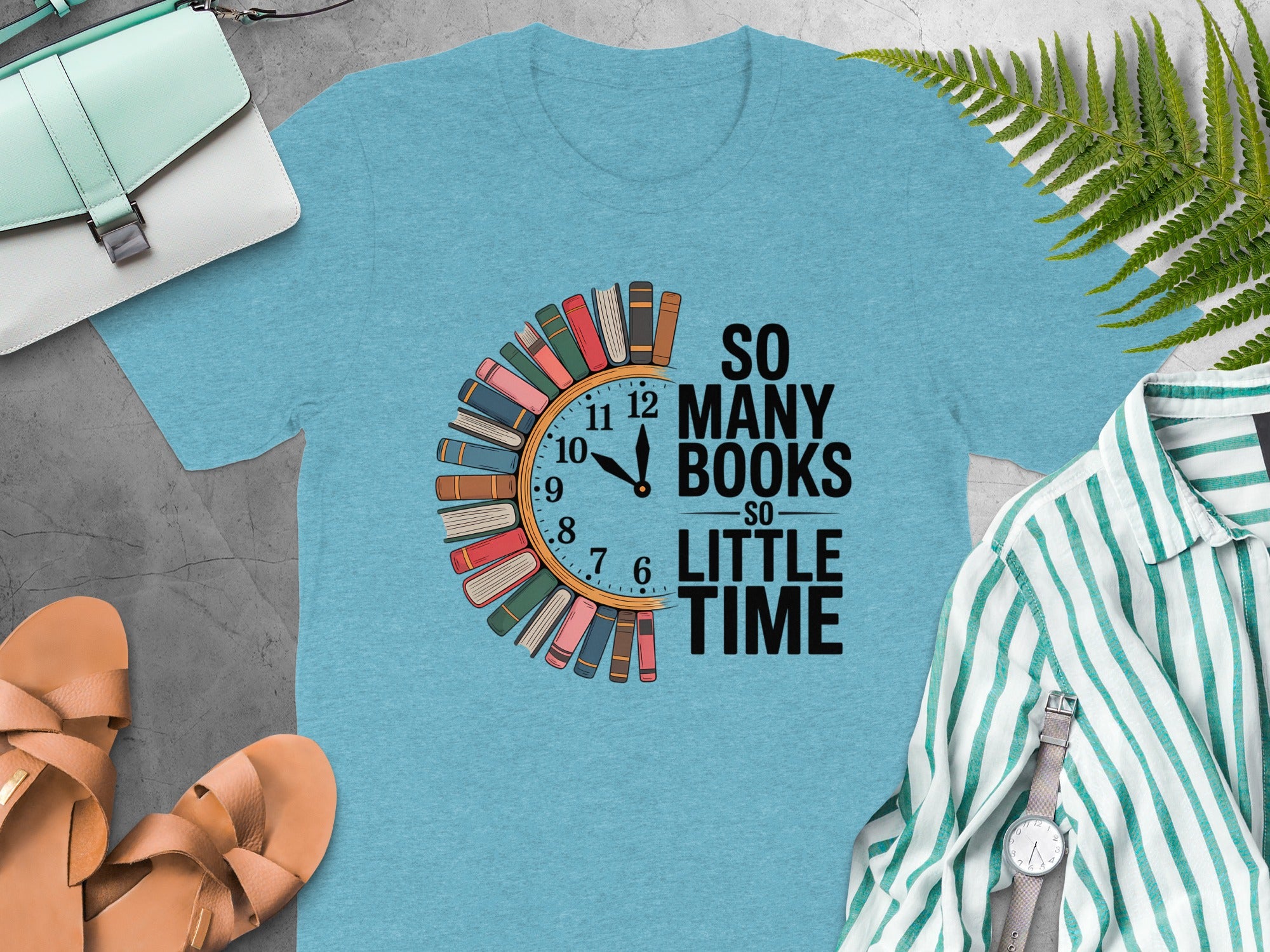 Light blue t-shirt with a clock graphic made of books and text "So Many Books So Little Time".