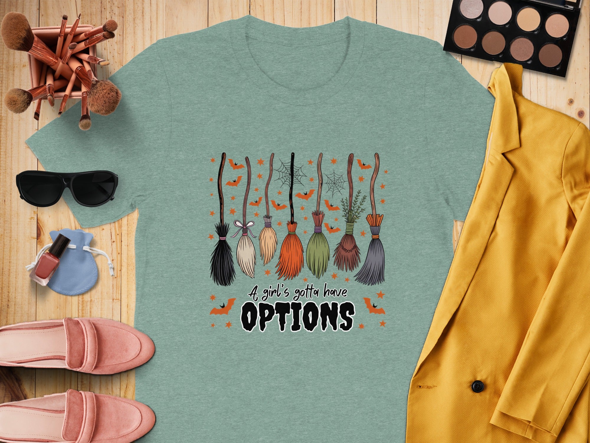 Light teal t-shirt with Halloween brooms, bats, and "A girl's gotta have OPTIONS" text.