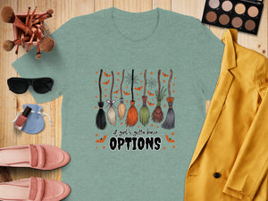 Light teal t-shirt with Halloween brooms, bats, and "A girl's gotta have OPTIONS" text.