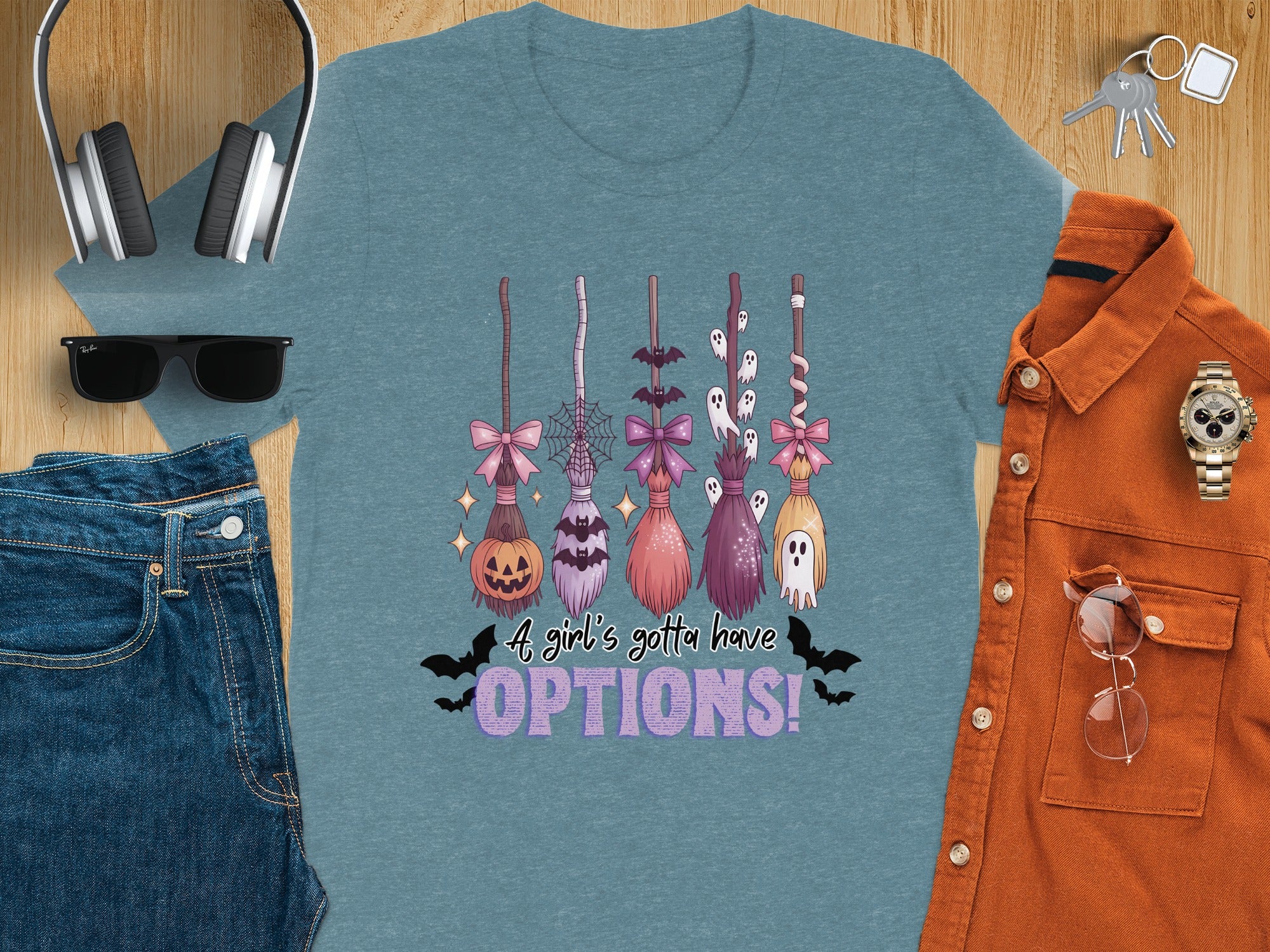 Teal t-shirt with Halloween brooms, pumpkin, ghosts, bats, and text "A girl's gotta have OPTIONS!"