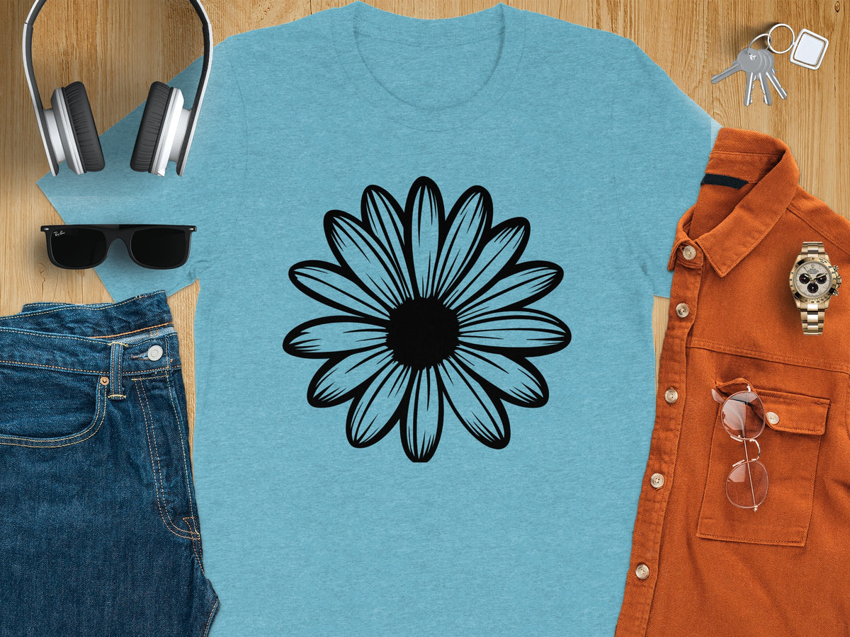 Light blue t-shirt with black daisy graphic, surrounded by jeans, headphones, sunglasses, shirt, watch, keys, and glasses.