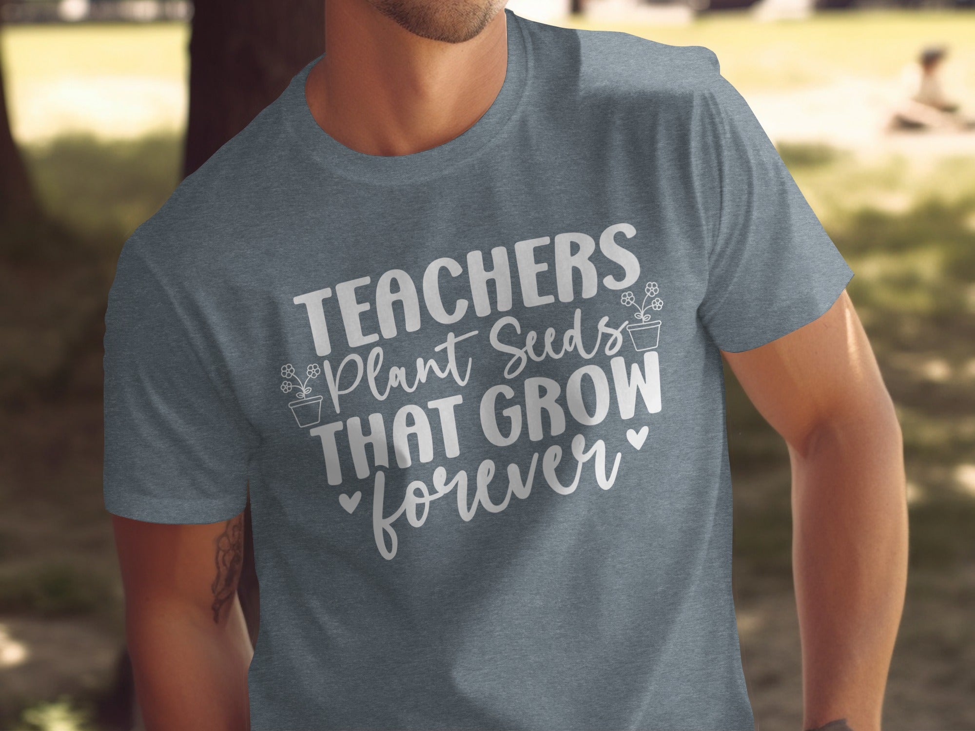 Grey t-shirt with white text that reads "TEACHERS Plant Seeds THAT GROW forever".
