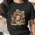 Chimpanzee wearing sunglasses, leopard print bow, and jewelry, holding up peace sign.