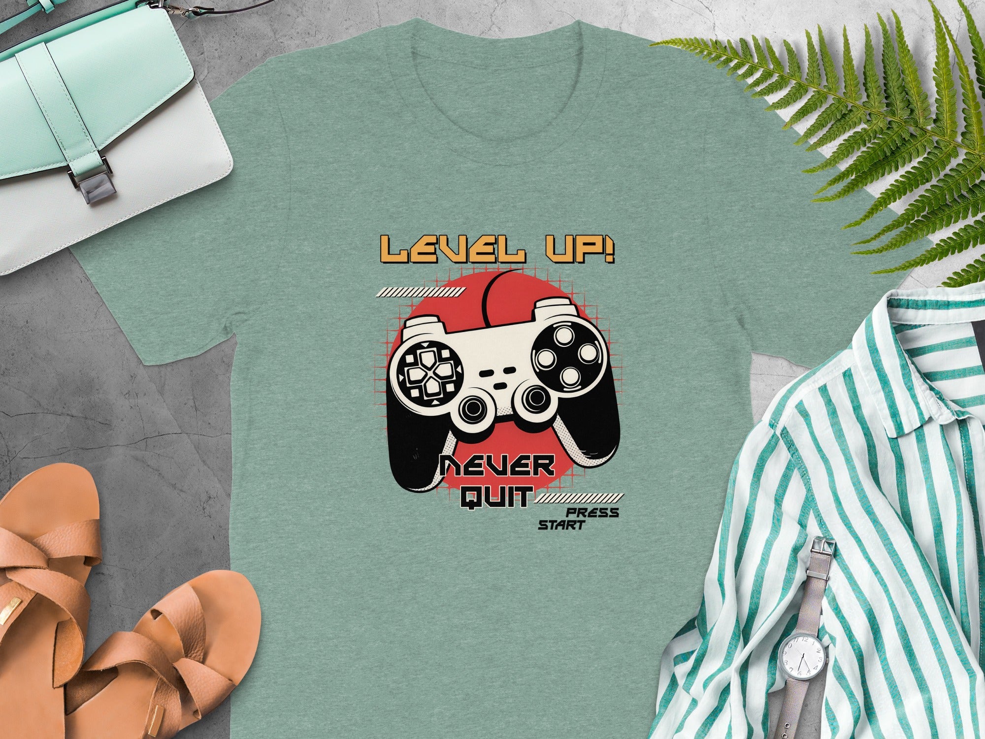 Green t-shirt with video game controller and "Level Up! Never Quit Press Start" text.