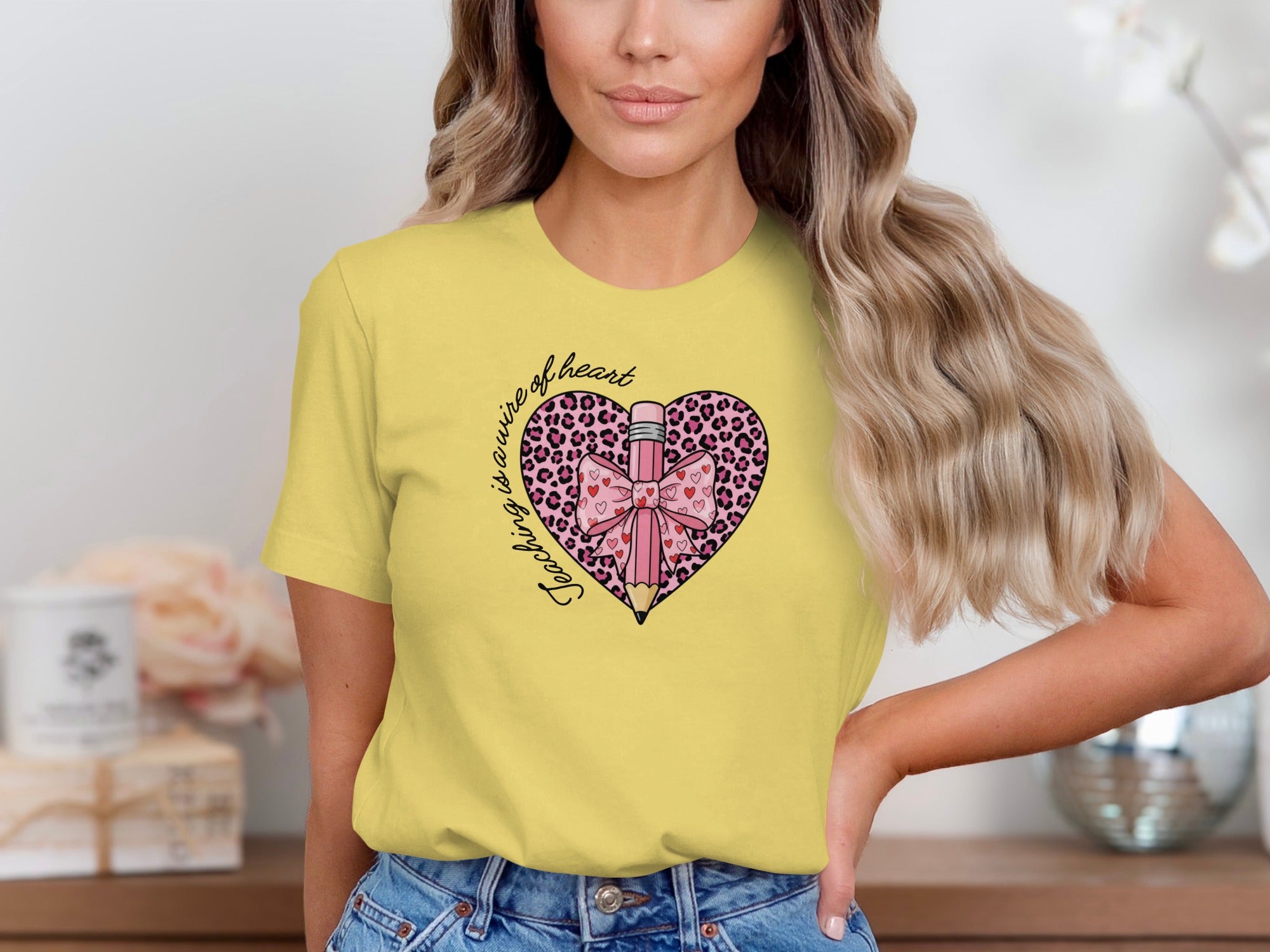 Yellow t-shirt with leopard print heart, pencil, bow, and text "Teaching is a work of heart."